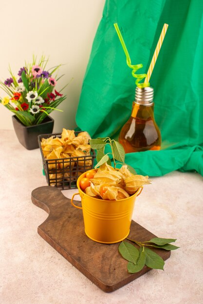 Free photo a front view orange peeled physalises inside basket with cocktail on the pink desk