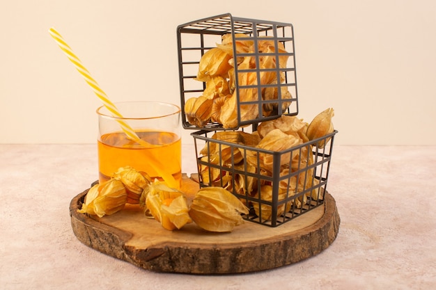 A front view orange peeled physalises inside black basket with drink on the pink desk  