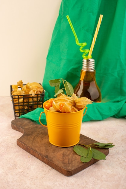 A front view orange peeled physalises inside bucket with cocktail on the pink desk 