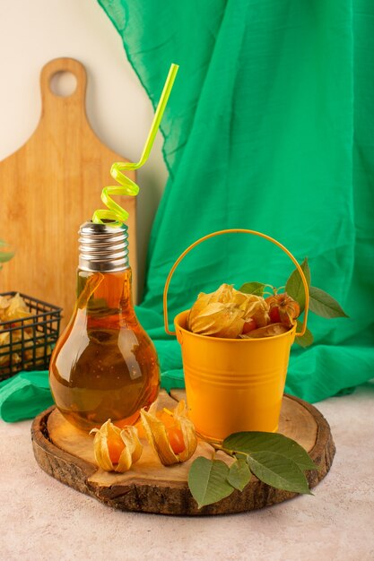 A front view orange peeled physalises inside bucket with cocktail on the pink desk 