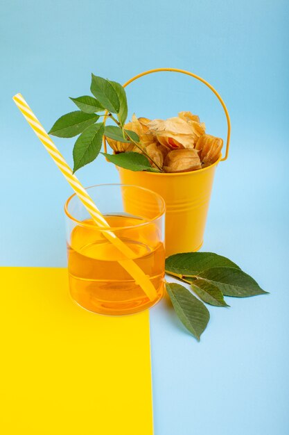 Очищенный апельсиновый физалис, вид спереди, в ведре с коктейлем на желто-синем столе
