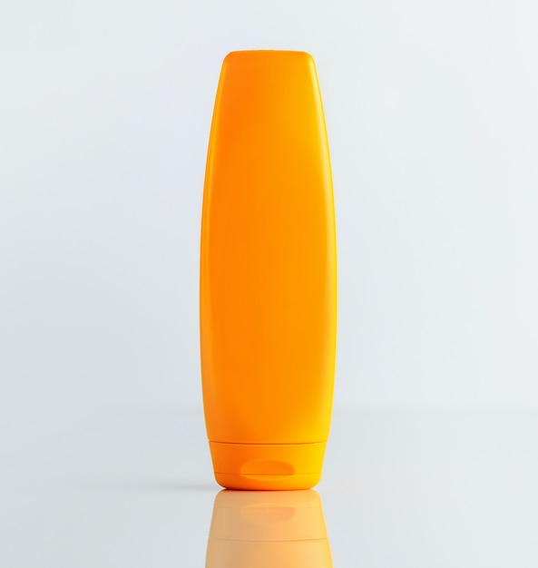 A front view orange shampoo bottle on the white wall