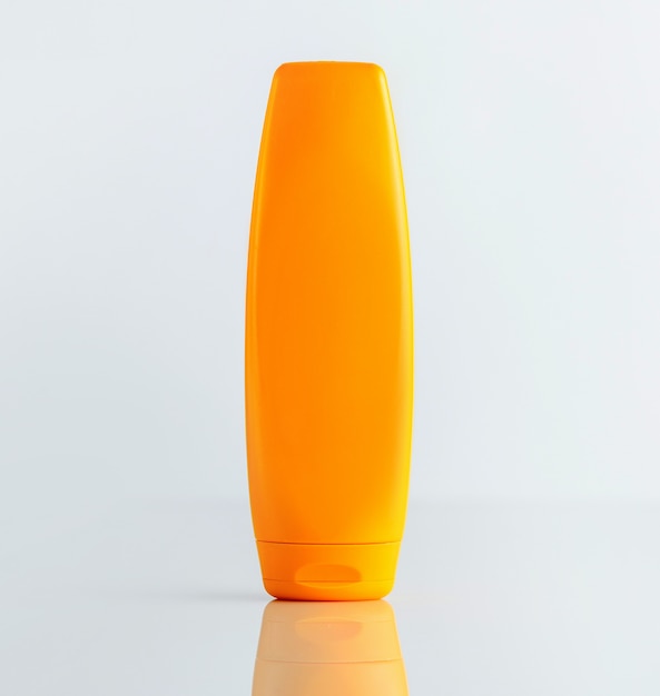 白い壁に正面図のオレンジ色のシャンプーボトル