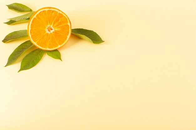クリーム色の背景の柑橘系の果物ジュースの夏に緑の葉とともに分離された正面オレンジスライス新鮮でまろやかなジューシーな完熟