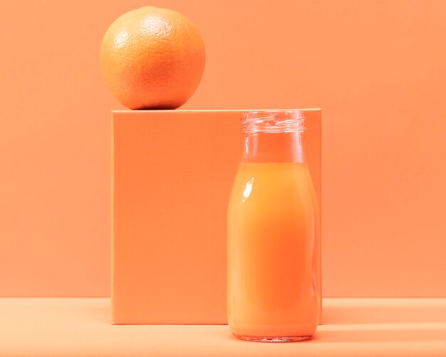 Front view orange and smoothie in bottle