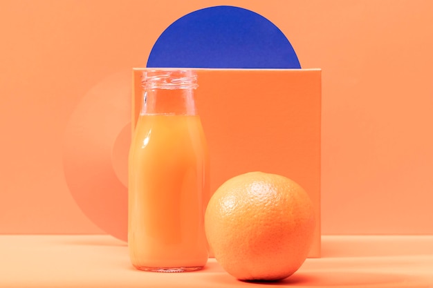 Free photo front view orange and smoothie in glass bottle