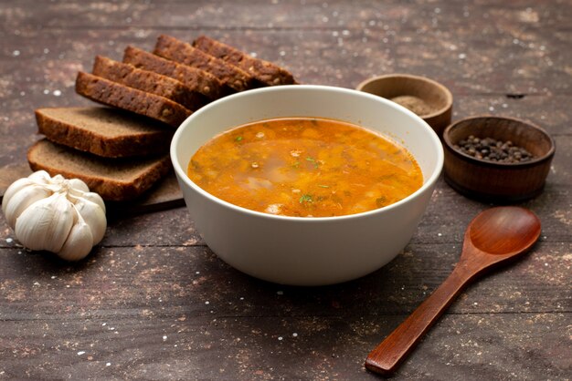 Вид спереди апельсиновый овощной суп с буханками хлеба и чесноком на коричневом, еда еда суп суп хлеб