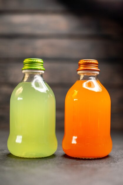 Вид спереди апельсиновый и желтый сок на темном фоне