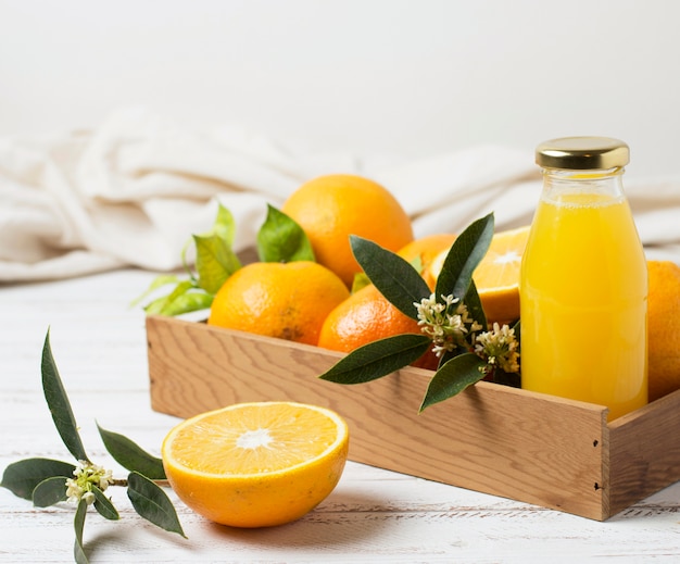 Вид спереди апельсинов и сока в деревянной коробке