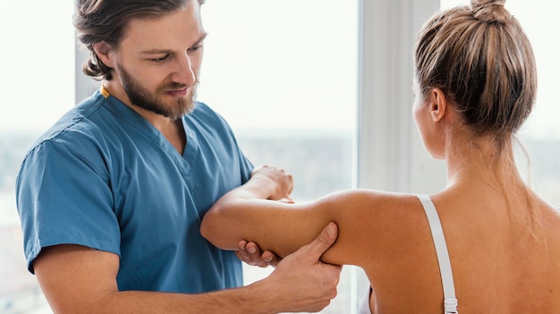 Free photo front view of osteopathic therapist checking female patient's shoulder movement