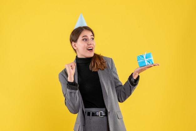 Front view overjoyed girl with party cap holding her gift