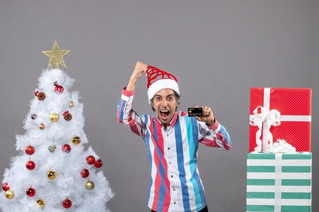 Front view overjoyed man in a victorious gesture standing near xmas tree