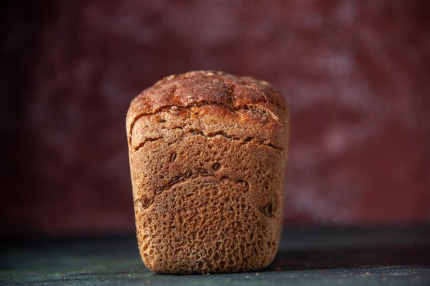 Front view of packed black bread on maroon distressed background with free space