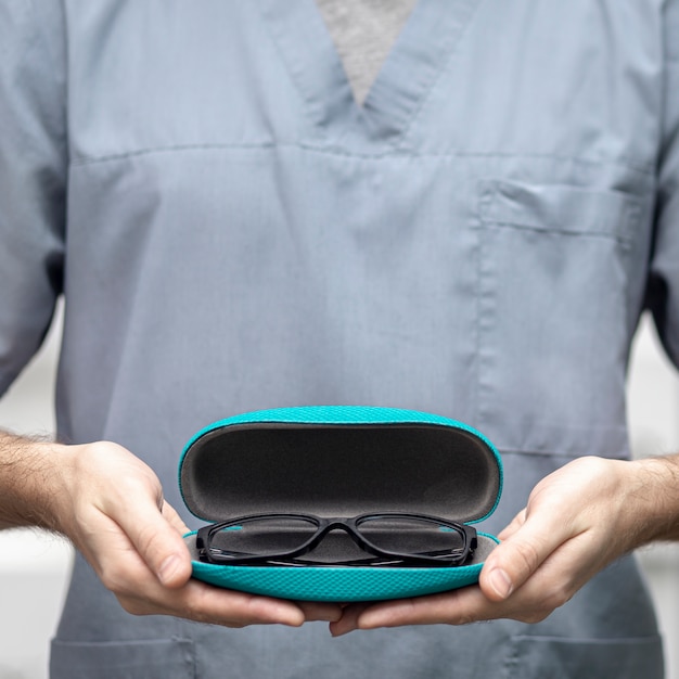 Free photo front view of pair of glasses in case held by man