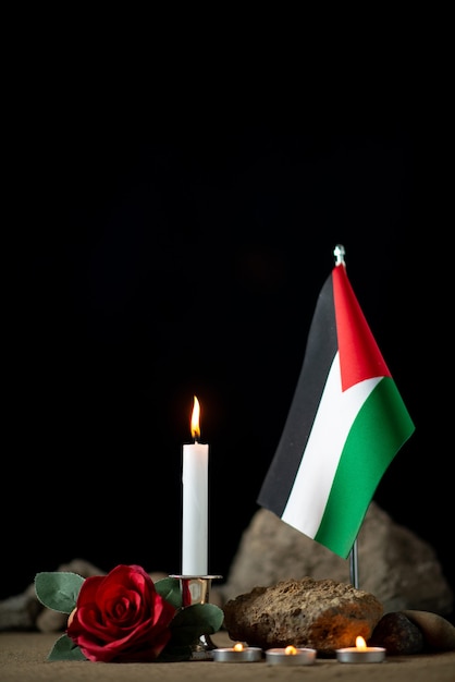 Front view of palestinian flag with burning candles on dark