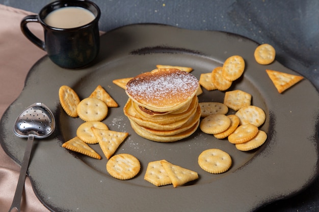 Frittelle di vista frontale e patatine con tazza di latte nera su grigio