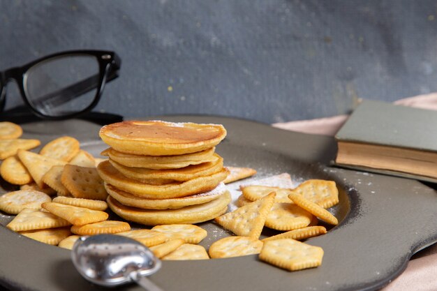 Front view pancakes with crackers inside plate with sunglasses on grey