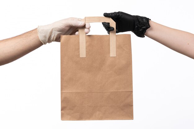 A front view paper food package being delivered from female to male both in gloves on white