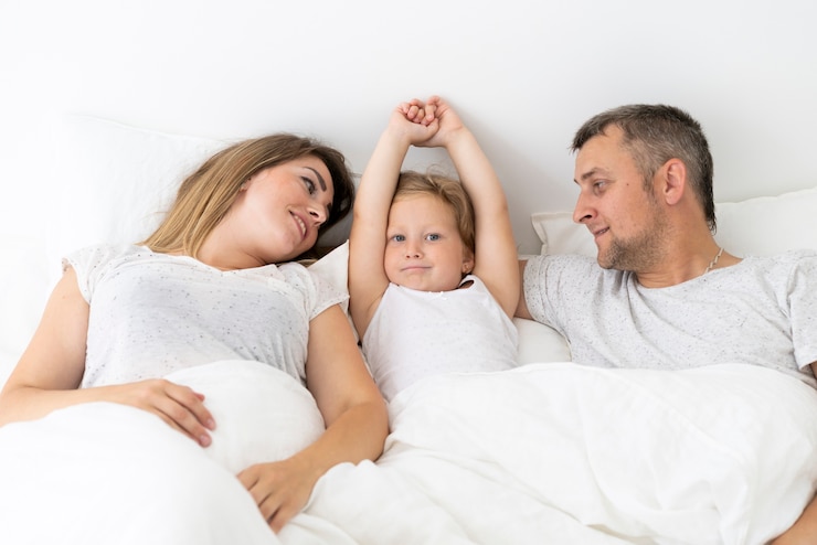 Бесплатный Фотография родитель вид спереди, сидя в постели с дочерью