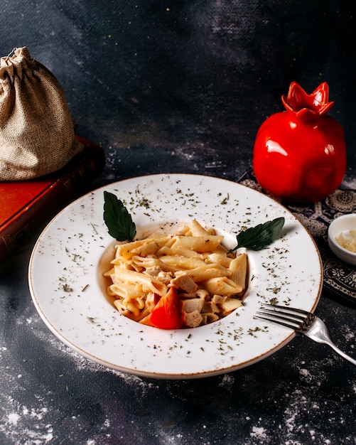 Foto gratuita pasta vista frontale cucinata insieme a foglie verdi all'interno del piatto bianco sulla superficie grigia