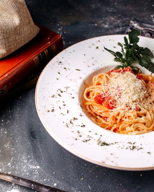 Front view pasta cooked tasty along with green leaf on the grey surface