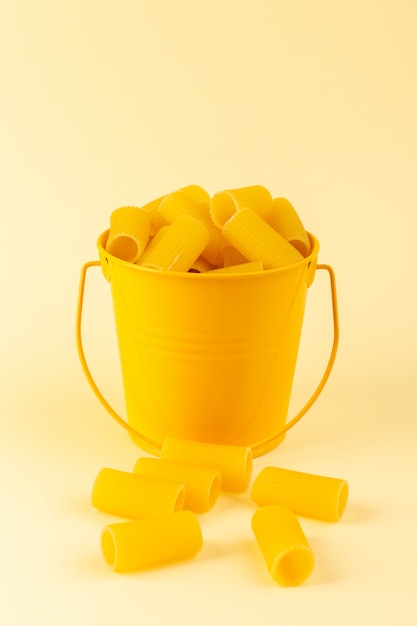 バスケットの中の正面図パスタは、クリーム色の背景に黄色のバスケットの内側に生を形成しました。食事食品イタリアンスパゲッティ