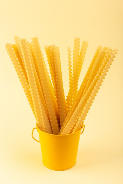 A front view pasta inside basket long formed raw inside yellow basket on the cream background meal food italian spaghetti