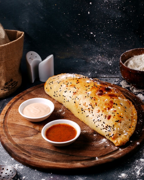 Free photo front view pastry along with white and red sauces on the brown wooden round desk and grey surface