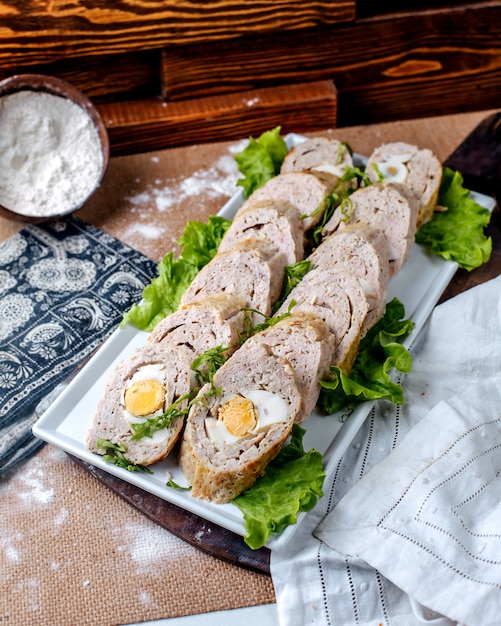 Foto gratuita il patè di vista frontale rotola insieme a insalata verde fresca dentro il piatto bianco sul pavimento marrone