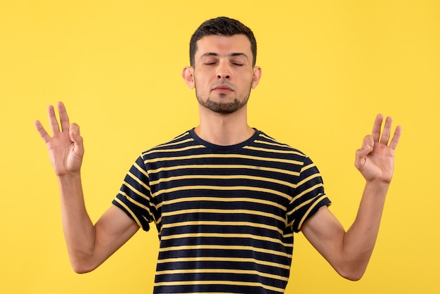 Free photo front view peaceful young man in black and white striped t-shirt yellow isolated background