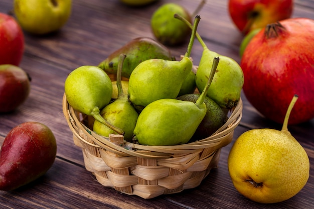 Вид спереди персики в корзине с другими и яблоки граната на деревянной поверхности