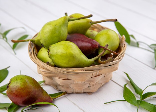 Front view of peaches in basket and on wooden surface decorated with leaves