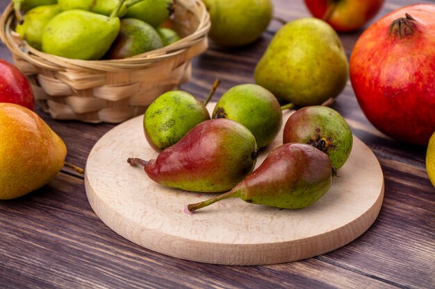 Front view of peaches on cutting board and in basket with other ones and pomegranate on wooden surface