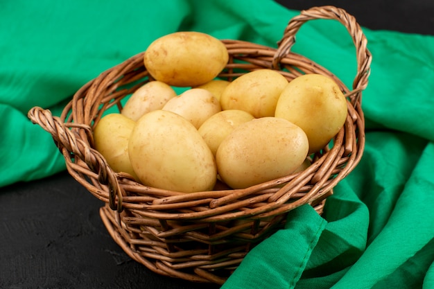 front view peeled out potatoes inside basket on the grey