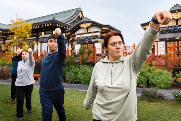 Free photo front view people practicing tai chi outside