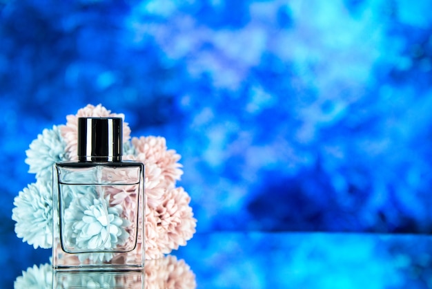 Free photo front view of perfume bottle flowers on blue blurred background with free place