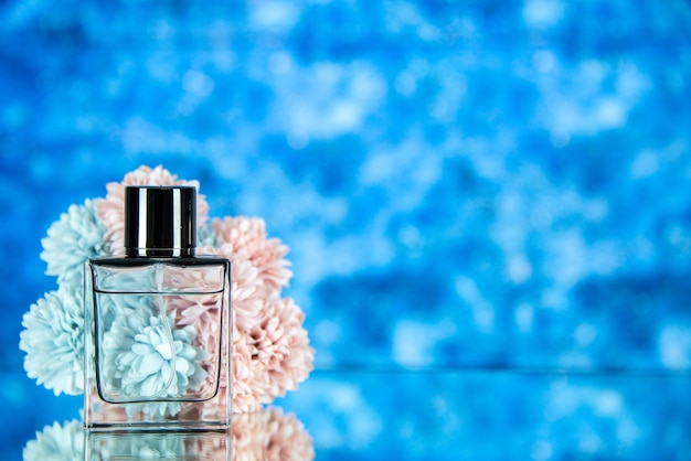 Free photo front view of perfume bottle flowers on blue blurred background with free space