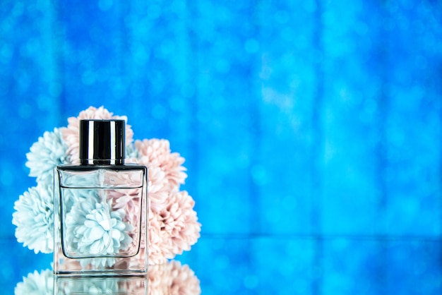 Free photo front view perfume bottle flowers on blue blurred background with free space