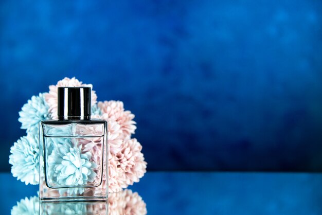 Front view of perfume bottle flowers on dark blue blurred background free space