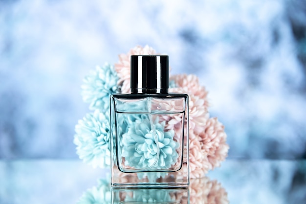 Front view of perfume bottle and flowers on ice blue blurred background