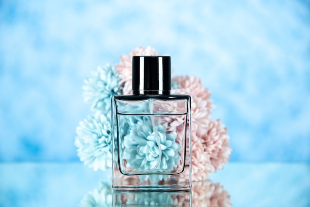 Front view of perfume bottle and flowers on light blue blurred background free space