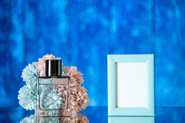 Free photo front view perfume bottle small blue photo frame flowers on blue background