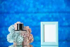 Free photo front view perfume bottle small blue picture frame flowers on blue background