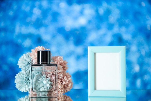 Front view perfume bottle small blue picture frame flowers isolated on blue background