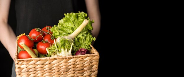 Front view person holding basket with veggies