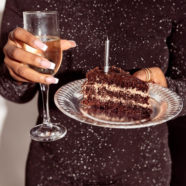 Front view person holding cake and champagne