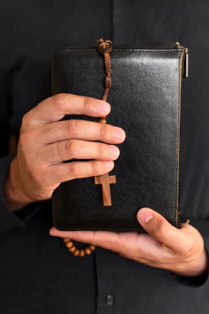 Front view of person holding holy book with rosary