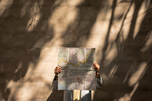 Front view person holding map over face