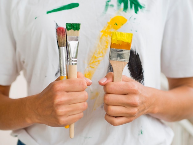 Front view of person holding paint brushes