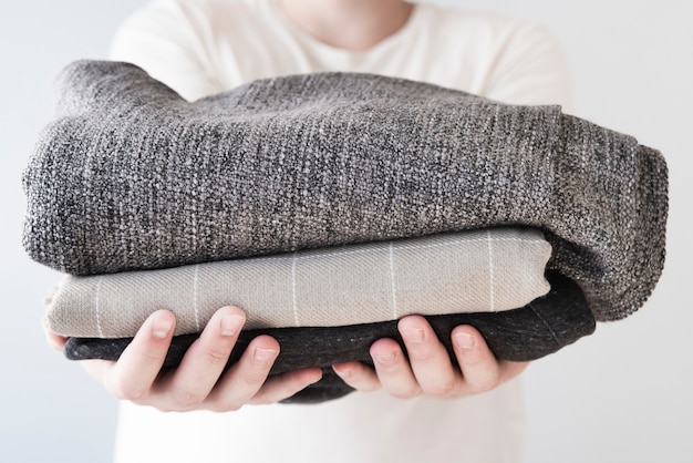 Front view person holding stacked laundry